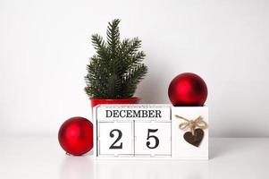 fundo de feriados em cores vermelhas, brancas e verdes com árvore de natal, enfeites e calendário foto