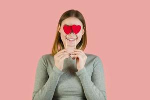 mulher loira sorridente com corações contra fundo rosa. retrato de estúdio do dia dos namorados foto