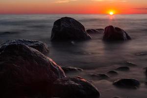 pedras na costa do mar báltico ao pôr do sol foto