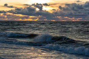 costa do mar báltico com seixos e gelo ao pôr do sol foto