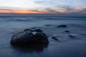 pedras na costa do mar báltico ao pôr do sol foto