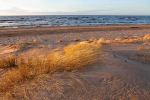 costa do mar báltico com seixos e gelo ao pôr do sol foto