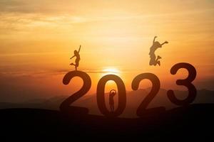 mulher salta feliz conceito de ano novo 2023, silhueta de mulher pulando sobre um penhasco de barreira e sucesso com fundo bonito por do sol. feliz ano novo 2023 use para banner e anúncio na web. foto