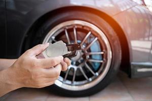 conceito de manutenção do carro, feche a mão de um homem segurando a trava da placa de freio e pastilha de freio na oficina foto