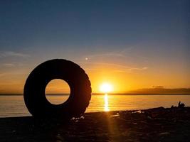 silhueta de objetos na praia com nascer do sol foto