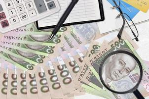 Notas de 500 hryvnias ucranianas e calculadora com óculos e caneta. conceito de temporada de pagamento de impostos ou soluções de investimento. procurando um emprego com salário alto foto