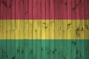 bandeira da bolívia retratada em cores brilhantes de tinta na parede de madeira velha. banner texturizado em fundo áspero foto