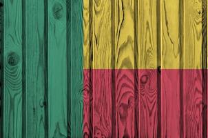 bandeira do benin retratada em cores brilhantes de tinta na parede de madeira velha. banner texturizado em fundo áspero foto