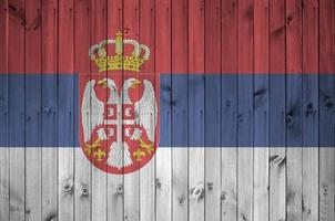 bandeira da sérvia retratada em cores brilhantes de tinta na parede de madeira velha. banner texturizado em fundo áspero foto