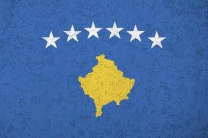 bandeira do kosovo retratada em cores de tinta brilhantes na parede de reboco em relevo antigo. banner texturizado em fundo áspero foto
