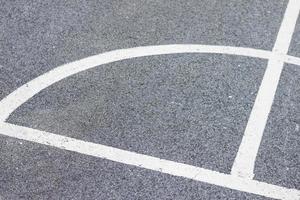marcações de linha branca para esportes no chão de asfalto preto. curva mostrando o ângulo. foto