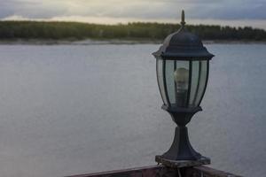 velhas lanternas situam-se à beira do rio ao entardecer com o pôr do sol. foto