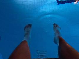 foto subaquática das pernas do homem na piscina