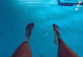 férias no mar na praia. pernas masculinas brancas. piscina com turquesa, água clorada, no fundo da grelha para purificação da água foto