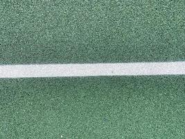 superfície de borracha verde de um bloco de segurança antitraumático de quadra de tênis em um playground esportivo em um parque ou pátio público. o fundo. textura foto