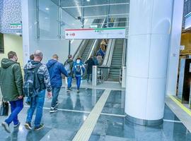 passagem subterrânea no metrô. as pessoas vão para a escada rolante para transferir para outra linha. viajar de transporte público, uma multidão de pessoas no metrô foto