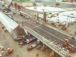 construção de uma nova ponte no centro da cidade, vista de cima. máquinas de construção está trabalhando na colocação de novo asfalto. marcação no inverno foto