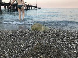 mulher moderna em traje de banho na beira-mar indo para o mar foto