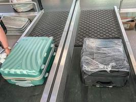 bagagem na fita no aeroporto. duas malas estão viajando ao longo da linha. as coisas estão empilhadas. malas embaladas em um filme transparente. a segurança das coisas foto