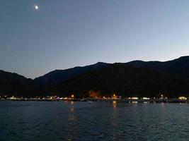 bela paisagem da Patagônia da Cordilheira dos Andes com altas montanhas com picos iluminados, pedras no lago da montanha, reflexão, céu violeta e nevoeiro ao pôr do sol foto