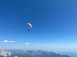 o pára-quedista voando alto no céu azul em um pára-quedas colorido foto