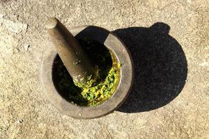 cozinhar pasta de pimentão verde tailandês em almofariz de pedra com pilão em uma rua. foto