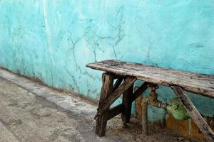 velho banco de madeira perto da velha parede azul e branca rachada. foto