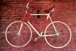 bicicleta velha em um fundo de parede de tijolo vermelho. Bangkok, Tailândia. foto