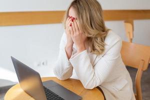 linda garota freelancer se sentindo cansada e estressada enquanto usa um laptop e trabalha remotamente em casa. mulher de negócios no escritório está deprimida. foto