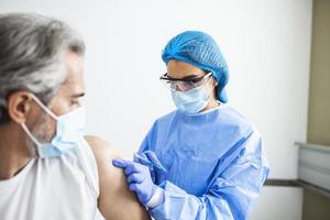 feche o médico segurando a seringa e usando algodão antes de fazer a injeção no paciente com máscara médica. vacina covid-19 ou coronavírus foto