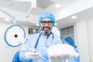 médico cirurgião sorrindo, segurando o implante mamário de silicone. implante mamário nas mãos do cirurgião foto