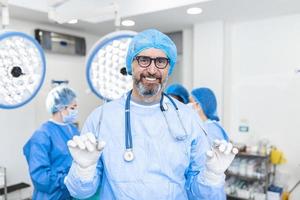 retrato de cirurgião masculino em pé na sala de cirurgia, pronto para trabalhar em um paciente. uniforme cirúrgico do trabalhador médico masculino no teatro de operação. foto