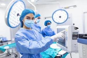 equipe diversificada de cirurgiões profissionais realizando cirurgia invasiva em um paciente na sala de cirurgia do hospital. enfermeira distribui instrumentos para cirurgião, anestesiologista monitora sinais vitais.