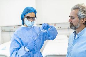 assistência médica segurando covid-19, kit de coleta de swab de coronavírus, usando luvas de máscara de traje de proteção, tubo de ensaio para coleta de amostra de paciente op np, processo de protocolo de teste de dna pcr foto