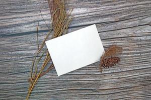 maquete de cartão de papel a5 com folhas secas em fundo de madeira foto