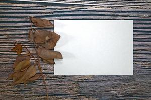 maquete de cartão de papel a5 com folhas secas em fundo de madeira foto