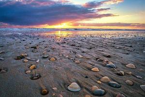 praia de areia com conchas e ondas ao fundo. na praia de blavand foto