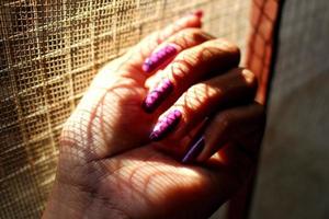 closeup da mão de uma mulher com unhas pintadas à luz do sol foto