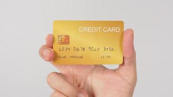 mão está segurando o cartão de crédito ouro isolado no fundo branco. foto