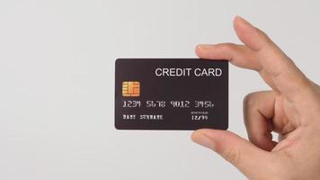 mão está segurando o cartão de crédito preto isolado no fundo branco. foto