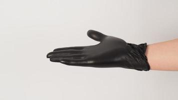 a mão está usando uma luva de látex preta e abra a palma da mão no fundo branco. foto