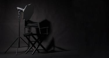 cadeira de diretor preto e luz de estúdio em fundo preto. foto