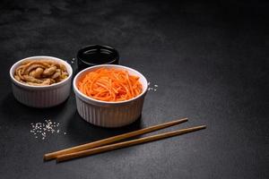 saborosa cenoura coreana picante com especiarias e ervas em um fundo escuro de concreto foto