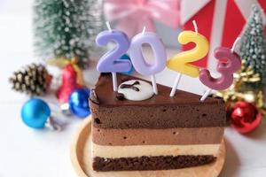 bolo de chocolate com números 2023 e acessórios para eventos de natal e ano novo isolados em fundo rosa. foto