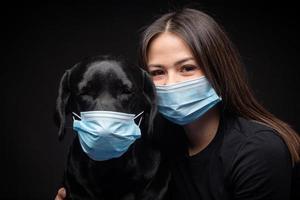 retrato de um cachorro labrador retriever em uma máscara médica protetora com uma dona. foto