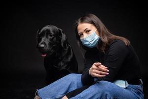 retrato de um cachorro labrador retriever em uma máscara médica protetora com uma dona. foto