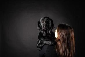 uma garota tem um cachorro labrador retriever nos braços. foto