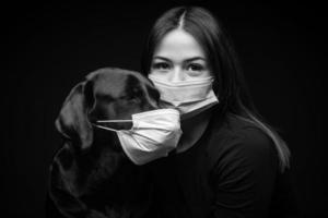 retrato de um cachorro labrador retriever em uma máscara médica protetora com uma dona. foto