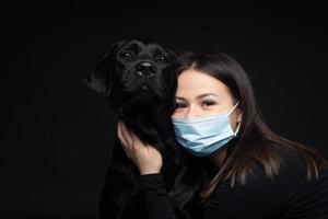 retrato de um cachorro labrador retriever em uma máscara médica protetora com uma dona. foto