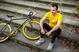 um jovem parou para descansar com sua bicicleta em um parque público. foto